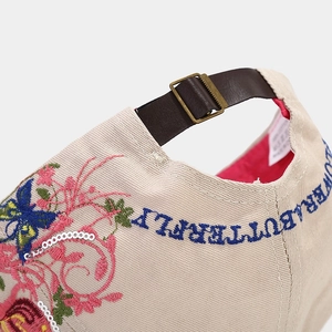Beige baseball cap with floral butterfly embroidery and sequin detail, back view with strap