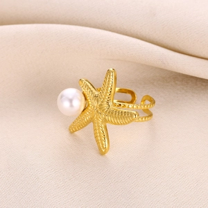 Golden starfish ring with faux pearl detail on beige fabric, elegant beach jewelry