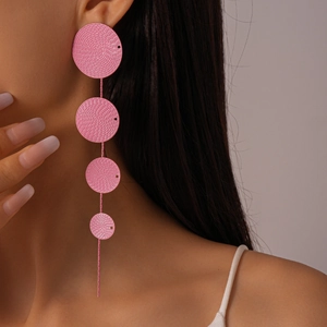 Close-up of pink layered geometric disc earrings worn by a model in a natural setting