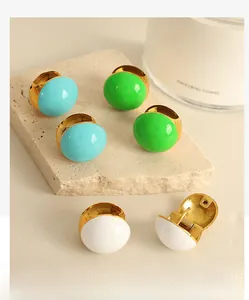 Detailed macro view of French retro enamel hoop earrings in blue, green, and ivory white