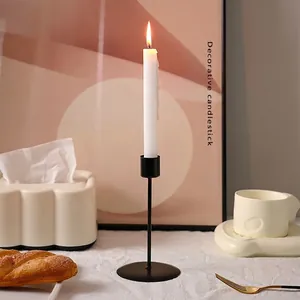Minimalist matte black metal candle holder with burning white candle for home dining decor