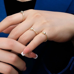 Detail of minimalist 18k gold plated heart rings worn by a model in a close-up view