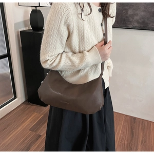 Detail of a dark brown PU leather hobo bag worn by a model in a modern home setting