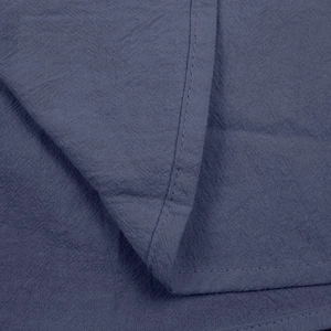 Close-up of blue linen sleeveless shirt fabric showing breathable texture and fine stitching