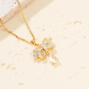 Elegant gold bow necklace with white cubic zirconia and a clear teardrop pendant