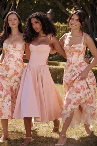 Close-up of three pink floral and solid sundresses with lace details in an outdoor garden