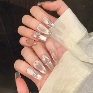 Dettaglio di unghie lunghe con glitter occhio di gatto champagne e farfalle metalliche 3D