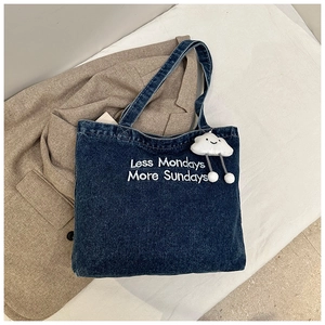 Détail du sac cabas en denim bleu avec broderie et pendentif décoratif en forme de nuage