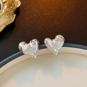 Gros plan détaillé de boucles d'oreilles cœur en argent avec texture de lave irrégulière