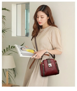 Detail of burgundy printed bucket bag showing gold metal lock and leather texture