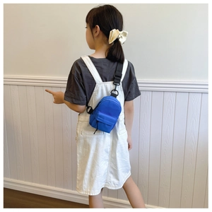 Rear view of a blue nylon mini crossbody bag worn by a child against a white wall