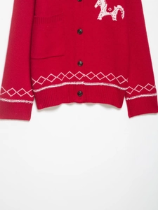Dettaglio cardigan in maglia rossa con ricamo di cavallo bianco e motivo a rombi