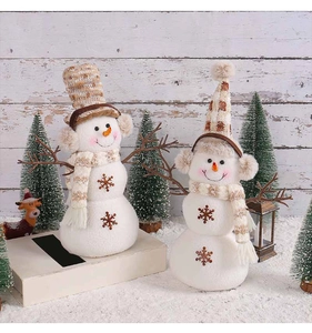 Close-up of two plush snowman figurines with knit hats and scarves on snowy background