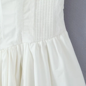 Detail of white dress showing lace trimming and pleated waist in ballet style