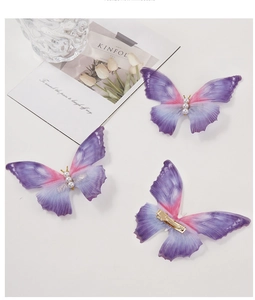 Detail of three purple and pink butterfly hair clips with pearls and golden duckbill clip
