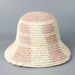 Detailed view of checkered pink and beige hand-woven straw bucket hat for sun protection
