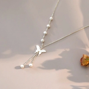 Detail of the elegant white butterfly pendant and multiple pearls on a silver chain