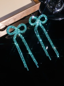 Macro shot of turquoise bow earrings featuring sparkling rhinestones and long tassel drops