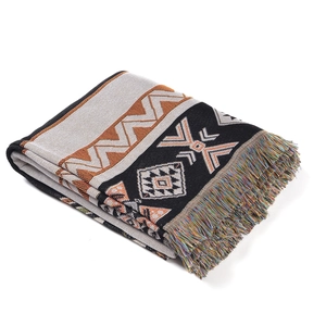 Detail of bohemian woven blanket featuring geometric patterns and colorful tassels