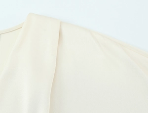 Detailed close-up of champagne satin blouse neck stitching and smooth fabric texture