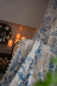 Detail of pine branch pattern curtains with fringe tassels in a cozy festive setting