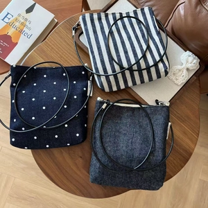 Overhead view of three vintage striped and denim crossbody bags on a wooden table