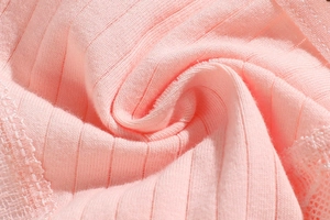 Macro detail of pink knitted fabric texture with delicate lace trim on low-rise thong
