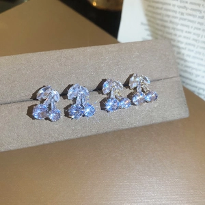 Macro shot of silver cherry stud earrings with sparkling cubic zirconia on grey velvet
