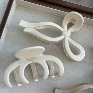 Detail of cream white hair claws with Only Belong to You gold script on linen texture