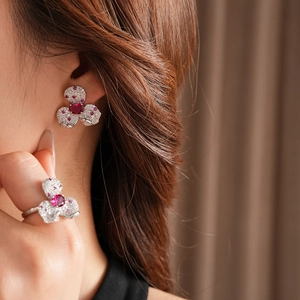 Detailed view of silver flower earrings and ring with red rubies and sparkling zircons