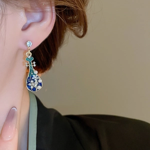 Close-up of elegant pipa-shaped earrings with pearls and crystals on a model