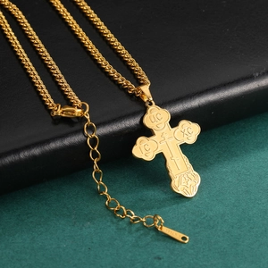 Detail of a golden stainless steel cross pendant with religious engraving on leather
