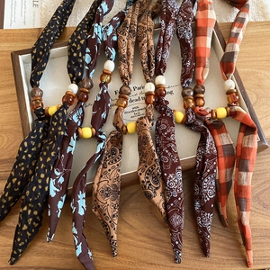 Detail of bohemian fabric beads necklace featuring paisley and leopard print patterns
