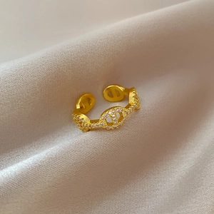 Detail of gold pig nose ring with sparkling cubic zirconia on beige silk