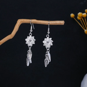 Macro detail of silver floral earrings with tassel hanging on a rustic branch