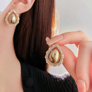 Detail of elegant gold teardrop earrings featuring a large pearl and sparkling zircon halo