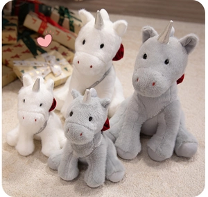 Detail of plush unicorn toys in white and grey colors with silver horns and ribbon