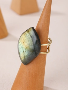 Macro shot of large natural labradorite stone set in a golden open ring on a wooden stand