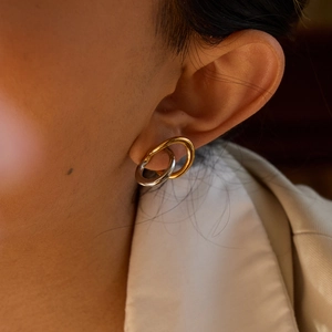 Close-up of interlocking gold and silver hoops on a model's ear for a modern look