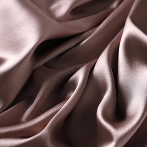 Macro shot of glossy satin fabric detail showing smooth texture and elegant drapes in dusty pink
