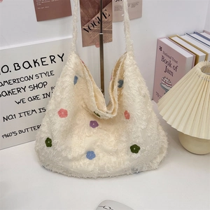 Detailed view of cream-colored plush tote bag with colorful embroidered floral patterns