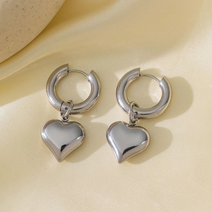 Close-up of silver titanium steel heart hoop earrings on elegant silk background