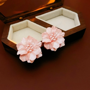 Détail macro de boucles d'oreilles fleurs roses avec perles sur boîte en bois