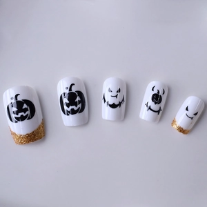 Faux ongles Halloween avec motifs citrouille et design French à paillettes dorées