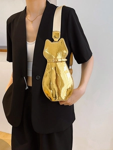 Glossy gold cat-shaped crossbody bag with a wide fabric strap shown on model