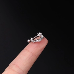 Macro view of a tiny silver butterfly cartilage earring with crystals on a fingertip