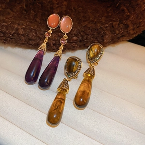 Detail of vintage teardrop earrings with purple and amber resin dangles and gold inlay