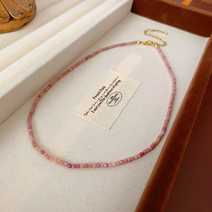 Détail macro du collier de perles roses avec fermoir doré dans un écrin à bijoux