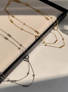 Detailed close-up of double-layered beaded titanium steel necklaces in gold and silver