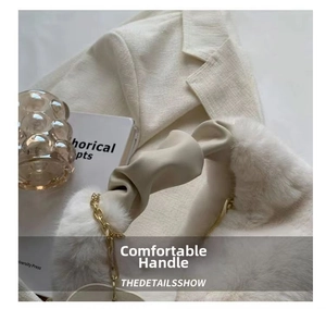 Detail of soft cream plush handbag with ruffled handle and elegant gold chain strap